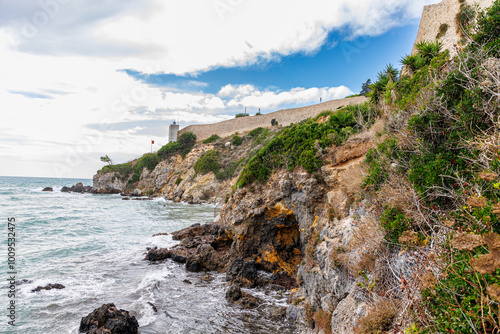 Scenic view of Talamone, a coastal town in Tuscany, Italy, perched on rocky cliffs overlooking the Mediterranean Sea. Traditional Italian architecture blends with lush greenery