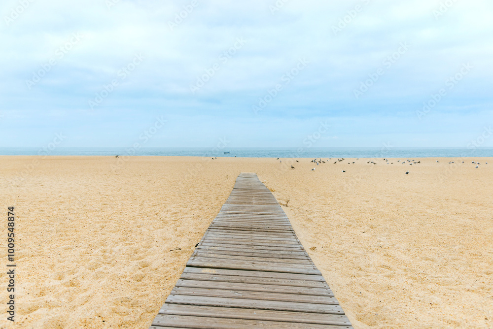 A wooden path leading across the sandy beach to the sea A wooden path leading across the sandy beach to the sea