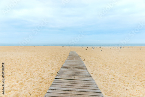 A wooden path leading across the sandy beach to the sea