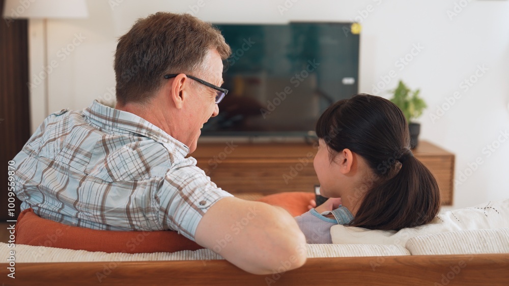 Grandfather and granddaughter together watch interesting entertainment media on TV. Old senior use technology communicate with young generation cross generation gap strengthen family bond. Divergence. Grandfather and granddaughter together watch interesting entertainment media on TV. Old senior use technology communicate with young generation cross generation gap strengthen family bond. Divergence.
