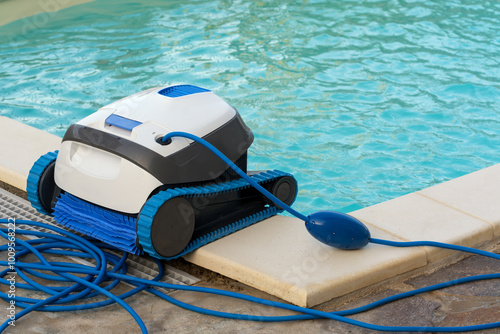 Pool Cleaner Robot stands on the edge of the pool with clear turquoise water after cleaning. Concept of pool cleaning in hotels, resorts and country houses.
