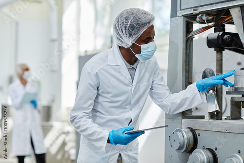 Obraz na plátne African American male process technician in lab coat looking inside manufacturin
