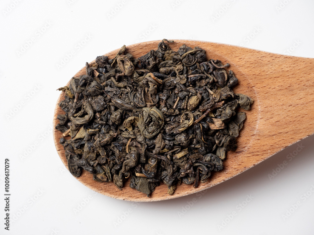 large wooden spoon on a white background. Green leaf tea is poured into a spoon. Tea party concept. Traditional Indian drink, top view. flat lay