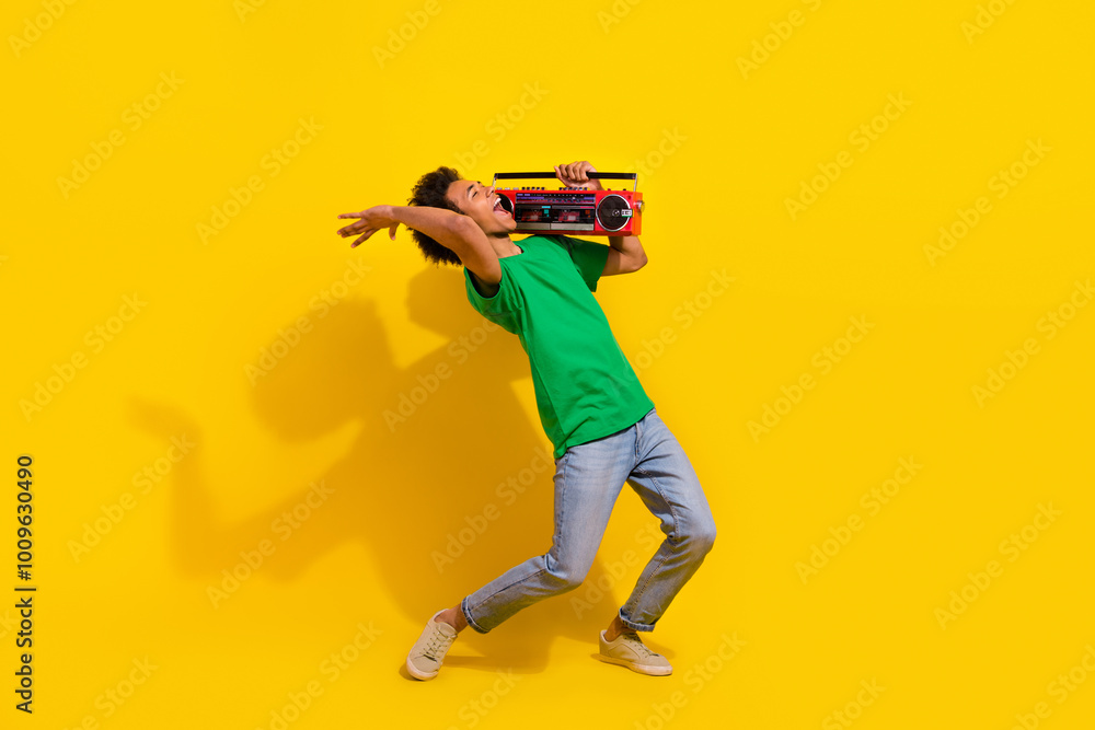 Full length photo of cheerful positive guy dressed green t-shirt singing listen boom box music emtpy space isolated yellow color background Full length photo of cheerful positive guy dressed green t-shirt singing listen boom box music emtpy space isolated yellow color background