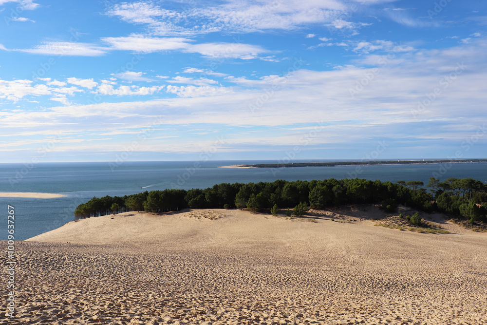 large sand dune with ocean and blue sky in the background large sand dune with ocean and blue sky in the background