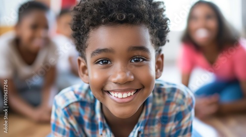 A young boy with curly hair beams with happiness while lying on the floor and interacting with his friends during a fun indoor playtime