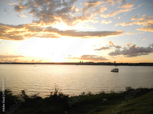 pequeno barco navegando em lago em um  final de tarde de um dia com nuvens rosadas no céu. photo