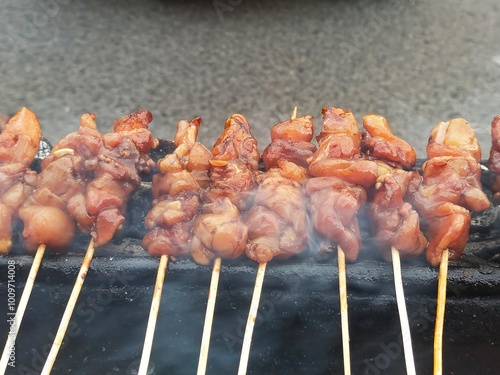 Rows of satay are being grilled while being fanned over hot coals and charcoal until the meat is cooked and smoky at a satay stall photo