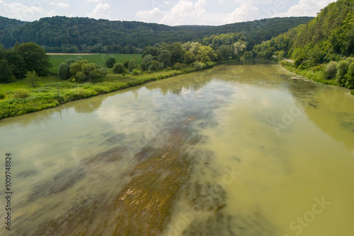 A peaceful river scene with lush greenery along the banks, reflecting the blue sky and clouds above. Perfect for nature-themed projects and publications. photo