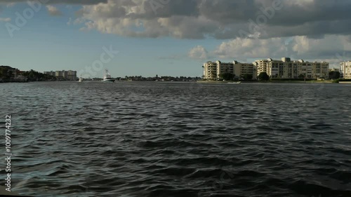 Time Lapse of three large motor boats passing left to right in bay water near sunset taken from St. Beach FL looking east. Large white and gray storm clouds and blue sky. North of drawbridge condos 