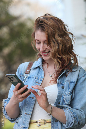 mid adult woman with cellphone text messaging  and smiling on the street photo