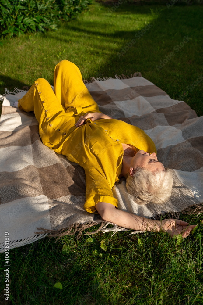 Mature woman resting in garden, eyes closed in sunny setting Mature woman resting in garden, eyes closed in sunny setting