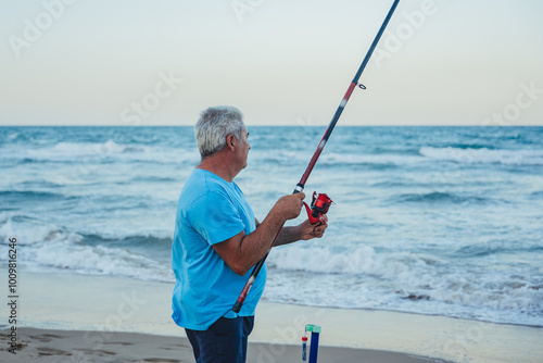 Elderly man fishing by the sea in Valencia, Spain photo