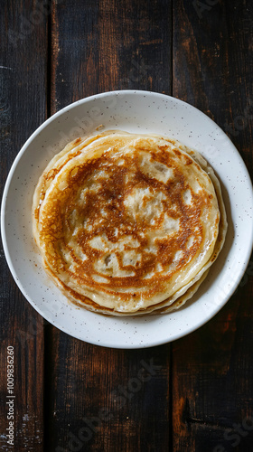 Delicious homemade pancakes stacked on a white plate, adding a cozy touch to the rustic wooden table