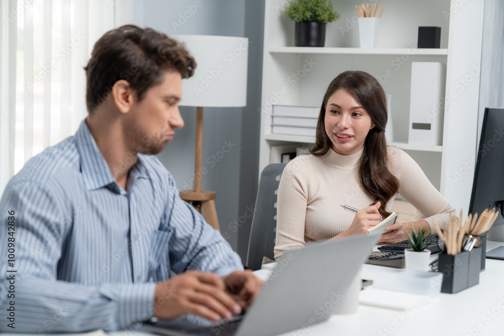 Smart manager talking to woman coworker while typing on laptop asking information data research project for business analysis report on desk at side view at modern office in morning time. Postulate. Smart manager talking to woman coworker while typing on laptop asking information data research project for business analysis report on desk at side view at modern office in morning time. Postulate.
