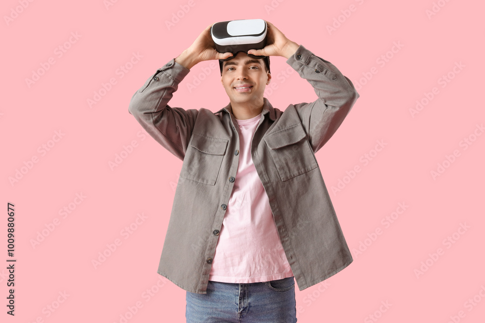 Happy young man with VR glasses on pink background Happy young man with VR glasses on pink background