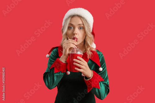 Photography Young woman dressed as elf drinking cola on red background