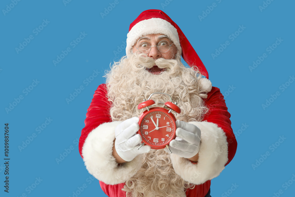 Shocked Santa Claus with alarm clock on blue background Shocked Santa Claus with alarm clock on blue background