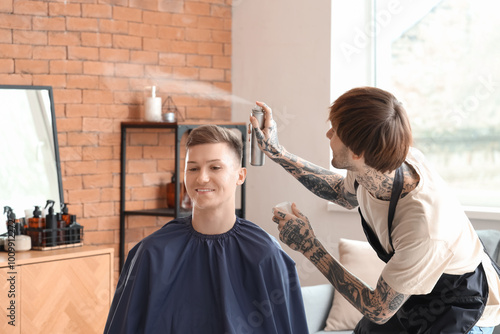 Male hairdresser spraying c...