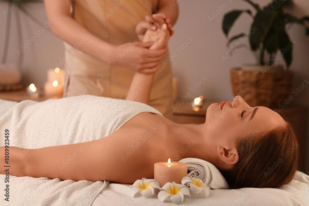 Young woman getting hand massage in dark spa salon