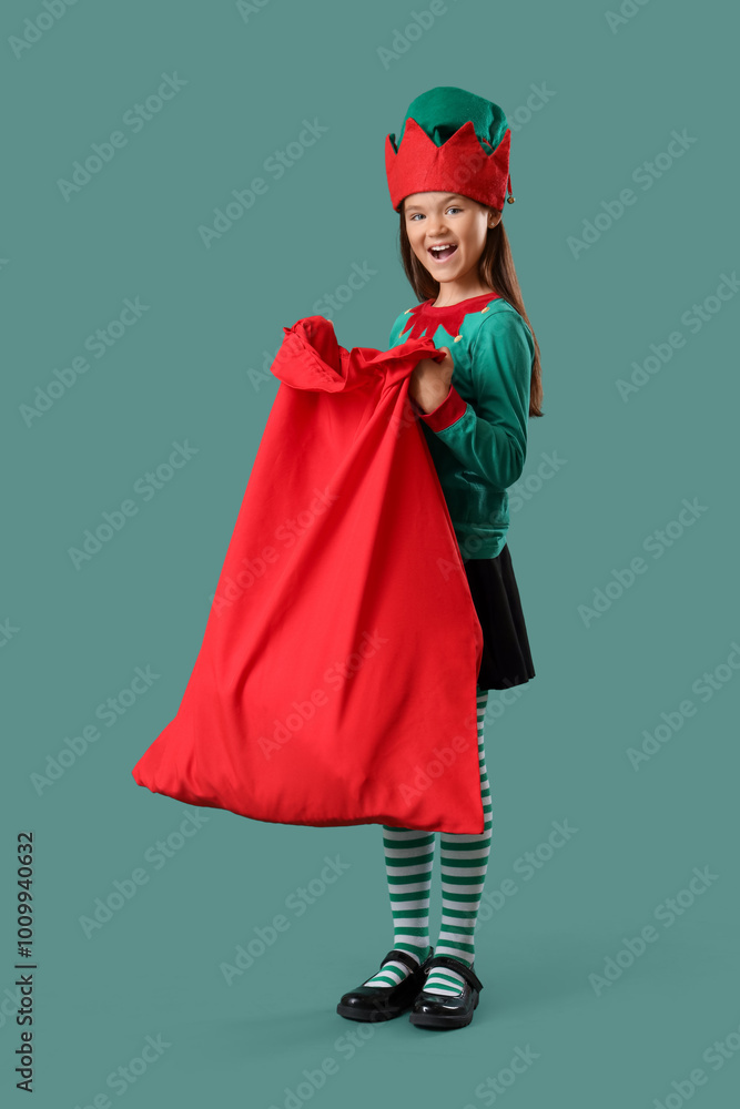 Little girl in elf costume with Santa bag on green background Little girl in elf costume with Santa bag on green background