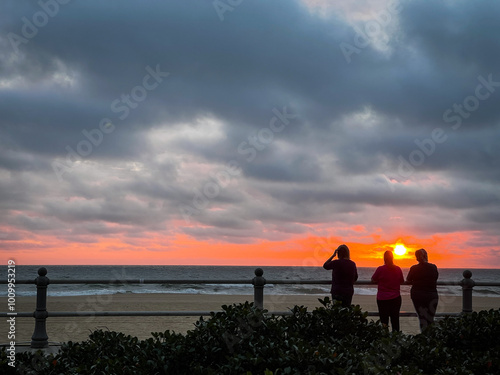 People enjoy the sunrise on the Virginia Beach boardwalk