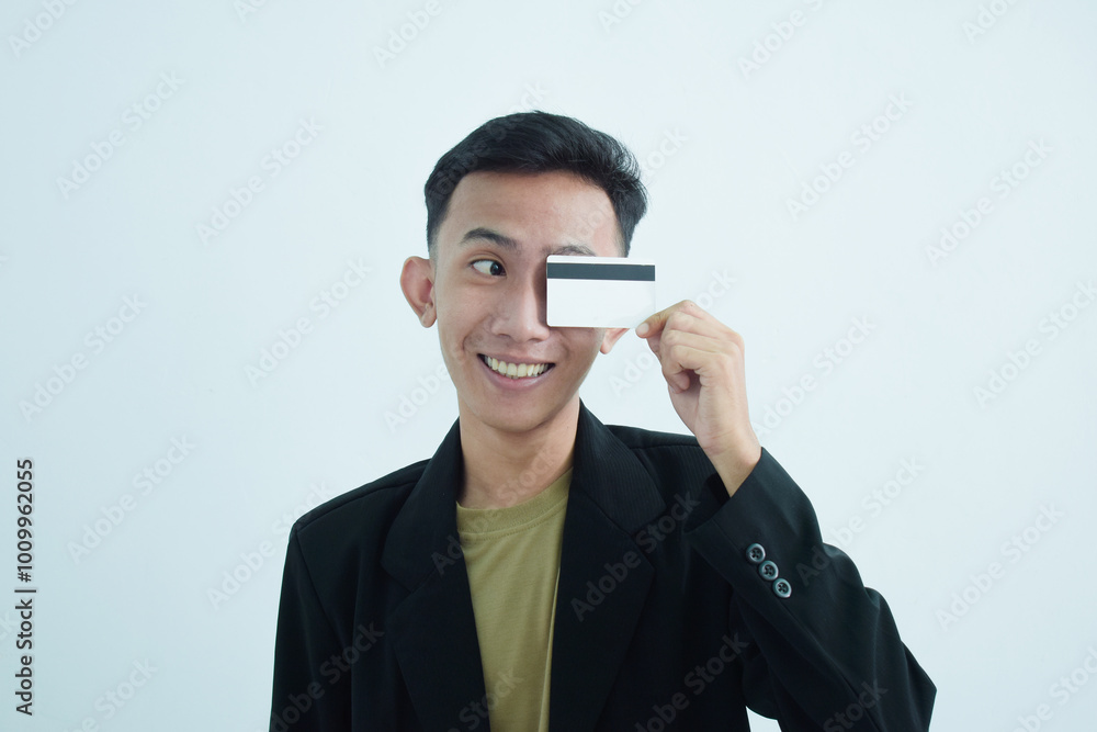 Joyful asian young businessman wear suit with tshirt and holding blank white credit card over white background Joyful asian young businessman wear suit with tshirt and holding blank white credit card over white background