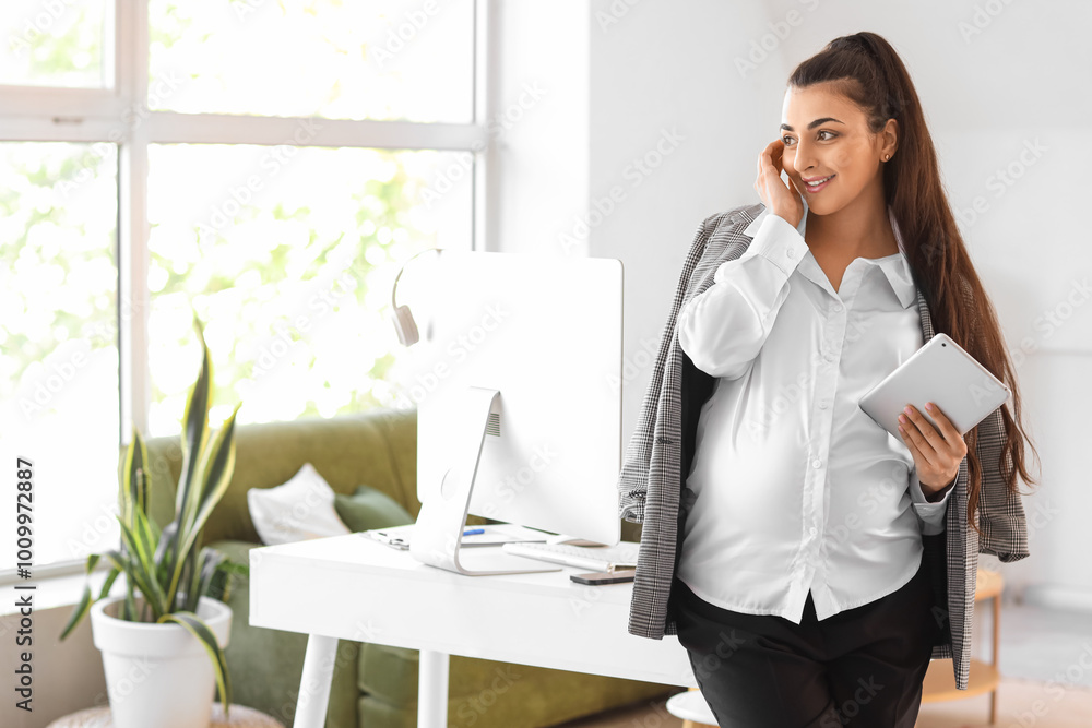 Pregnant businesswoman with tablet computer smiling in office