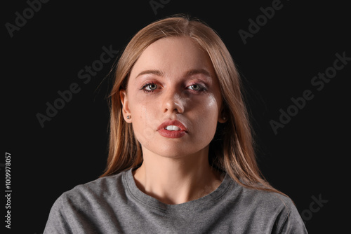 Young woman crying on black background, closeup photo