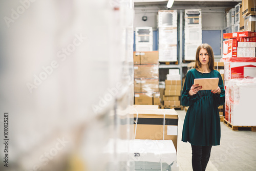 The young female warehouse owner checking the temperature, energy consumption and lights on a tablet. Close up. Smart systems.