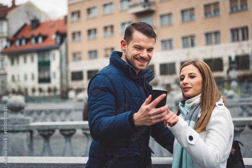 A couple walks in the centre of the capital. Man showing photo on smartphone he take to a woman. Couple travel. Modern instagram influencers. A couple walks in the centre of the capital. Man showing photo on smartphone he take to a woman. Couple travel. Modern instagram influencers.