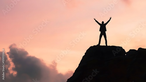 Silhouette of a man standing on a mountaintop with arms raised in the air, celebrating success against a pink and orange sunset.