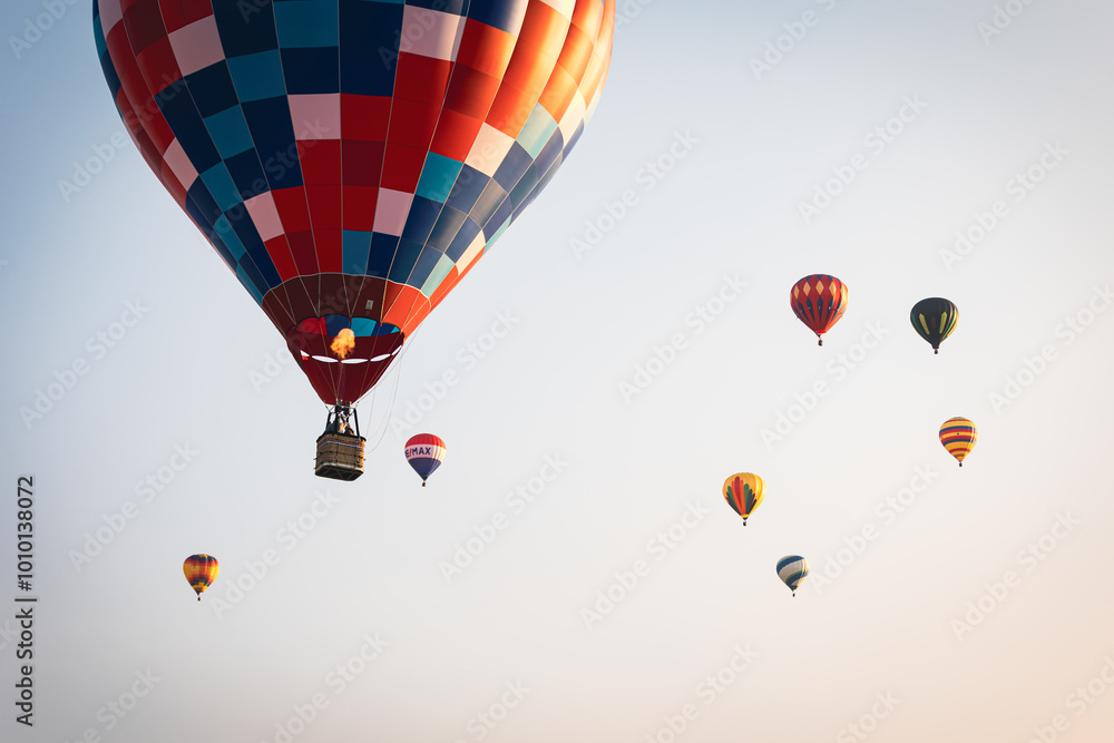 Fototapeta premium Horizontal view of Hot air balloon at sunrise against blue sky with more hot air balloons in distance