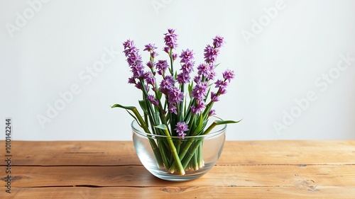 Wallpaper Mural A delicate arrangement of vertical bamboo shoots placed in a clear glass bowl, centered on a rustic wooden table against a serene, undecorated background. Torontodigital.ca