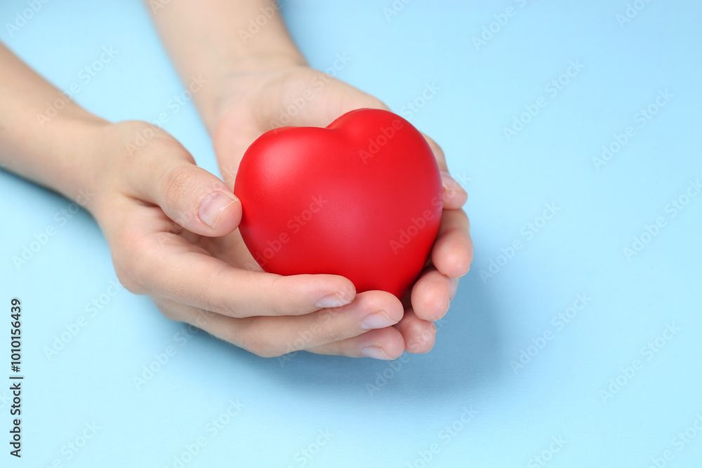 Woman holding red heart on light blue background, closeup Woman holding red heart on light blue background, closeup