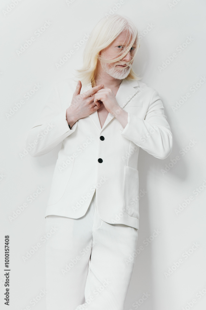 Fashionable man in white attire posing against a minimalist white background, showcasing modern style and elegance with long hair and a beard Fashionable man in white attire posing against a minimalist white background, showcasing modern style and elegance with long hair and a beard