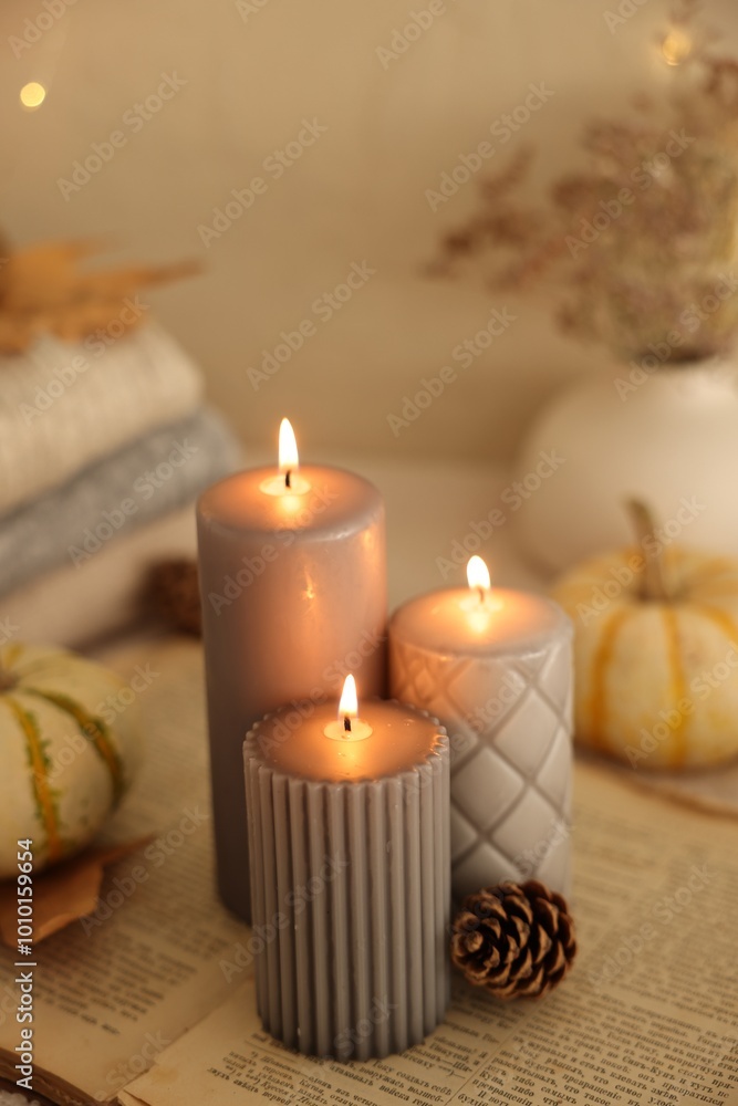 Burning candles and cone on book indoors. Autumn atmosphere Burning candles and cone on book indoors. Autumn atmosphere