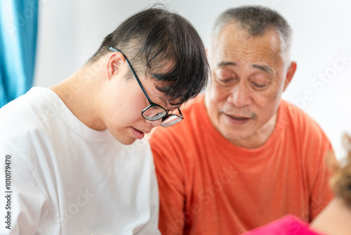 Senior man and grandchild practice math skill, interactive math game, Grandfather supervising grandchild sitting at sofa doing homework