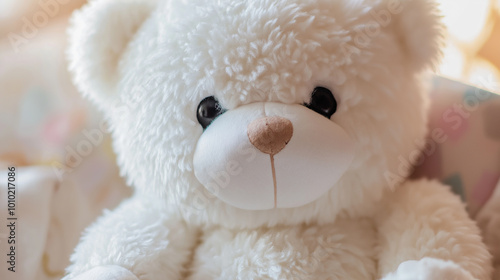 White fluffy teddy bear sitting on a bed with a pink blanket