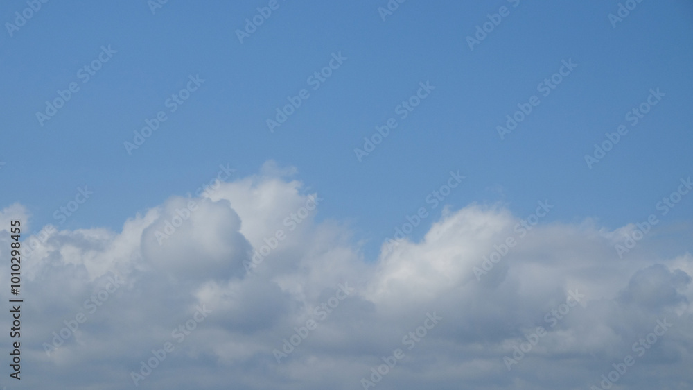 Blue sky with dramatic white clouds in abstract shapes, patterns and textures. Clumpy clouds in the blue sky. For graphic design or banner background Blue sky with dramatic white clouds in abstract shapes, patterns and textures. Clumpy clouds in the blue sky. For graphic design or banner background