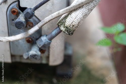 A dirty air conditioner unit with a white cord wrapped around it