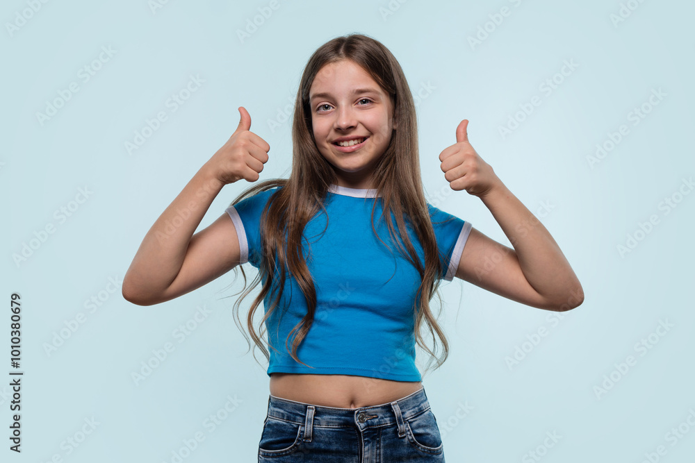 Young girl in blue top confidently gives a thumbs-up. Young girl in blue top confidently gives a thumbs-up.