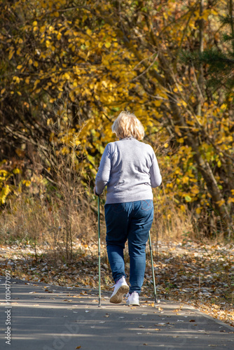 A woman is walking on a path with a pair of walking sticks