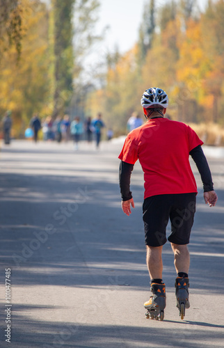 A man in a red shirt is riding a pair of roller skates down a road