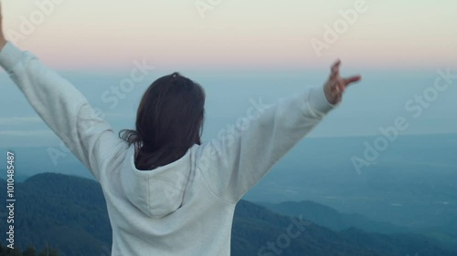 Woman raises hands up standing back on mountain top morning sun shine slow motion. Female silhouette figure in sportswear enjoy life wanderlust world. Person stretching after waking up 
