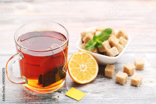 Cup of tea with lemon and sugar cubes on wooden table