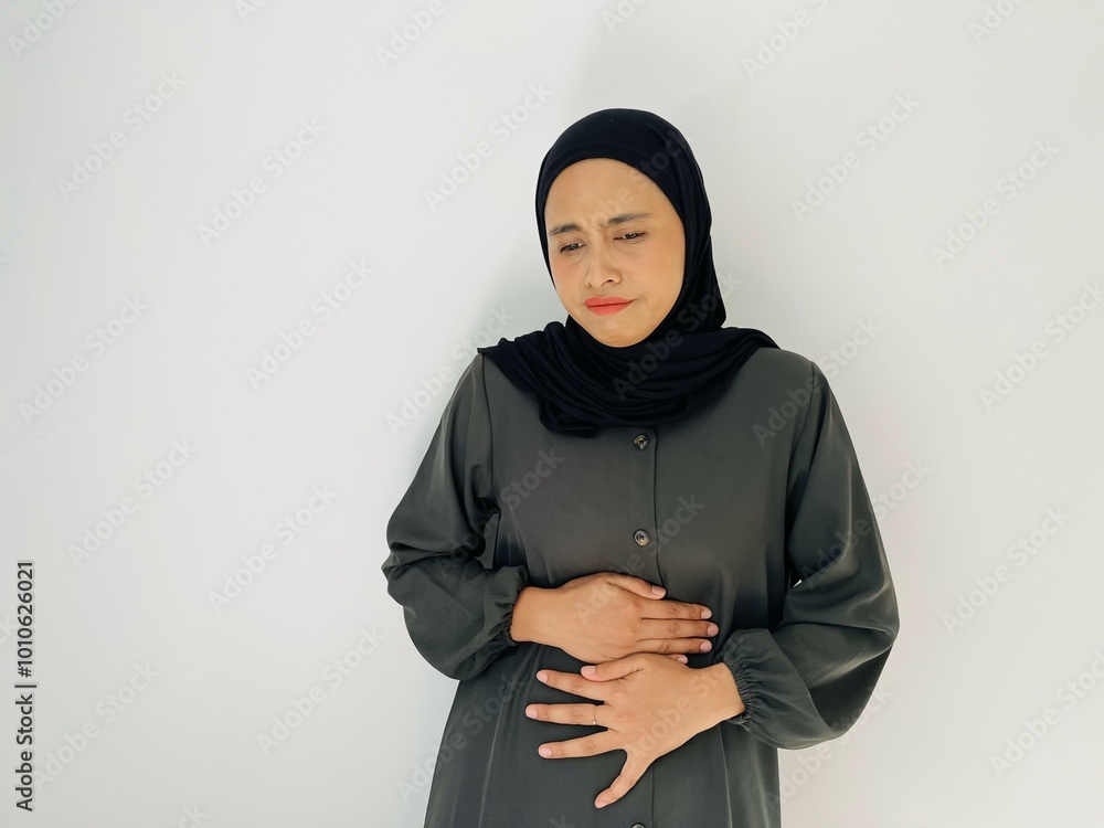 Asian Muslim woman suffering from stomach ache isolated on white background. Constipation, Menstruation, sick and health care concept. Asian Muslim woman suffering from stomach ache isolated on white background. Constipation, Menstruation, sick and health care concept.