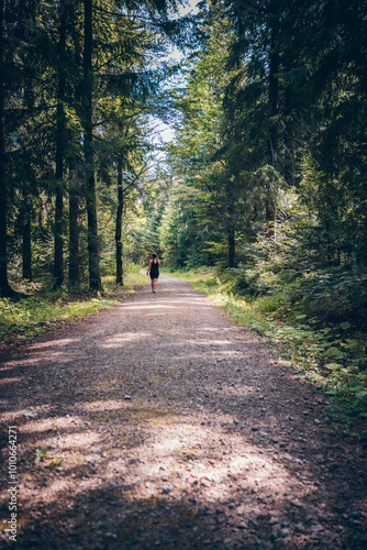 Person beim Spaziergang auf einem Waldweg im Sommer