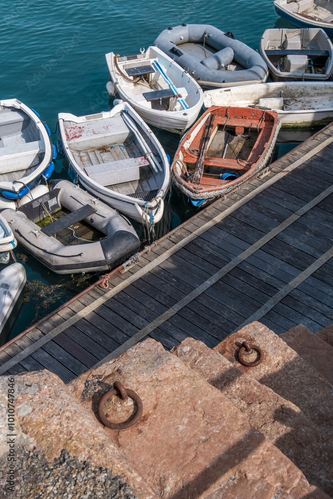 Group of small boats moored at a wooden quay with granite steps leading down to the water. St. Aubin's Harbour, Jersey, Channel Islands. Group of small boats moored at a wooden quay with granite steps leading down to the water. St. Aubin's Harbour, Jersey, Channel Islands.