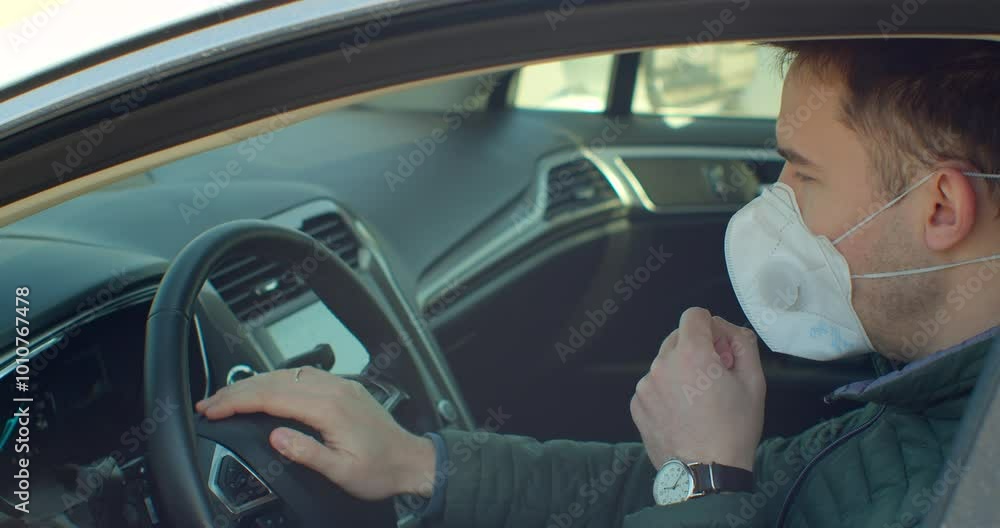 A man in a car coughs up a mask. Pandemic. Coronavirus. COVID-19. A man in a car coughs up a mask. Pandemic. Coronavirus. COVID-19.